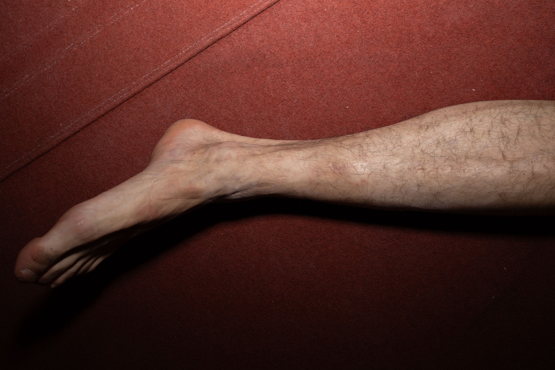 A bare leg resting against a deep red surface